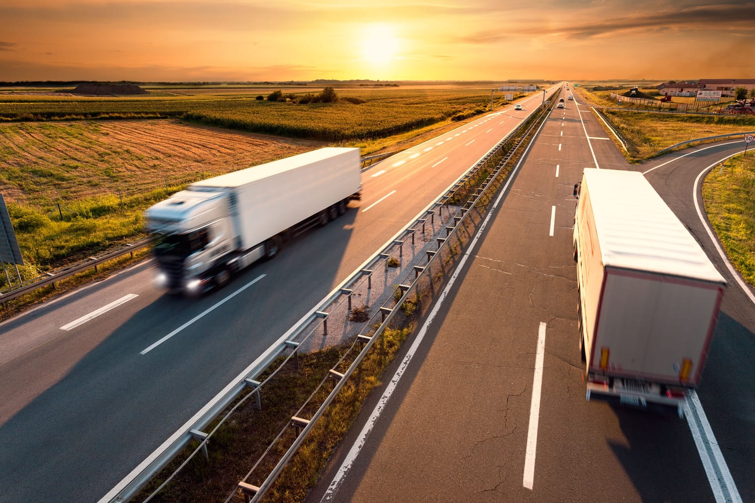 Camioane de marfă în mers pe o autostradă la apus